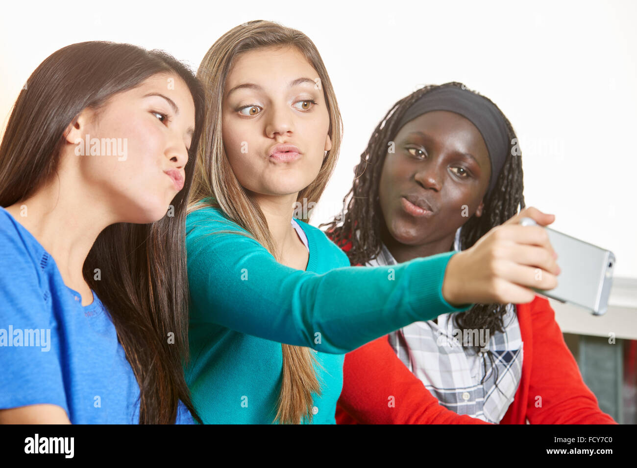 Three teenage girls taking a selfie and making silly faces at school Stock Photo