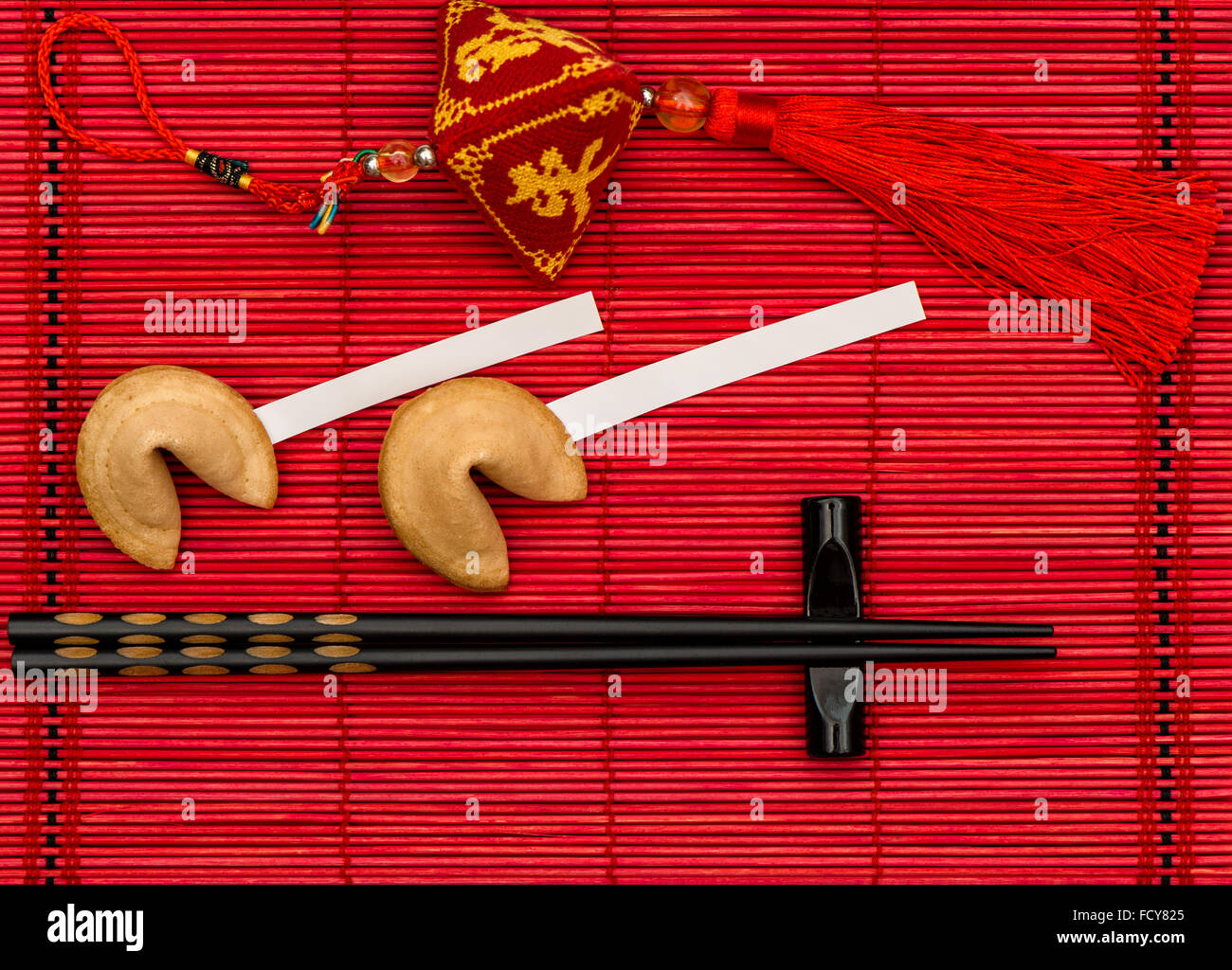 Chinese new years lucky charm, fortune cookies and black chopsticks on red bamboo mat Stock Photo