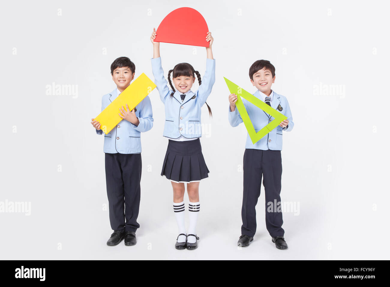 Three elementary school students holding big rulers for math each and ...