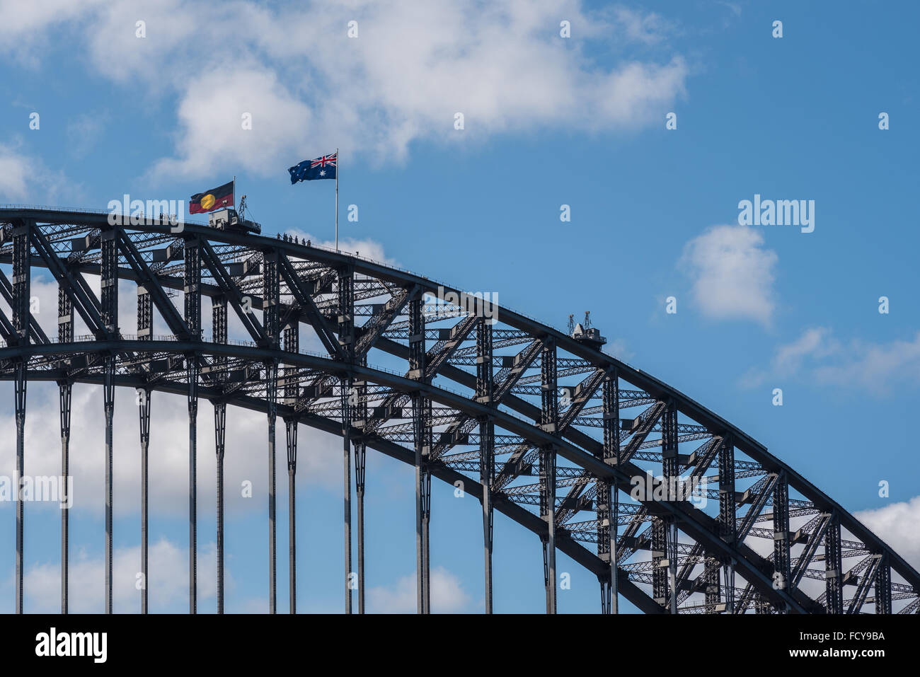Sydney Harbor Bridge with Aboriginal flag. Taking the usual spot for the flag of the state of New South Wales, the Aboriginal flag flies on the day commemorated as on which white settlement started in 1788. For Aboriginal peoples and protesters, the 26 January is sometimes called 'Invasion Day'. Credit:  Duncan Sharrocks/Alamy Live News Stock Photo