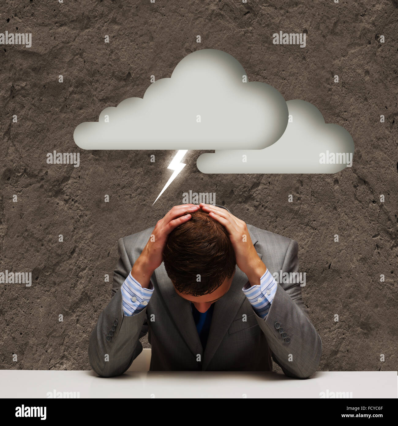 Depressed young businessman sitting wet under rain Stock Photo