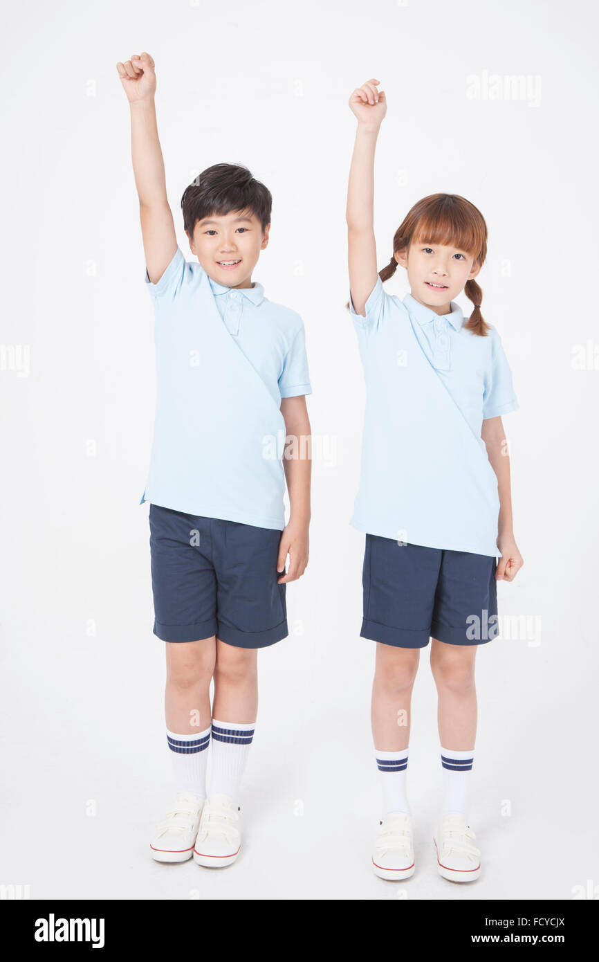 Two elementary school students in sportswear standing and staring forward with their hand up high Stock Photo