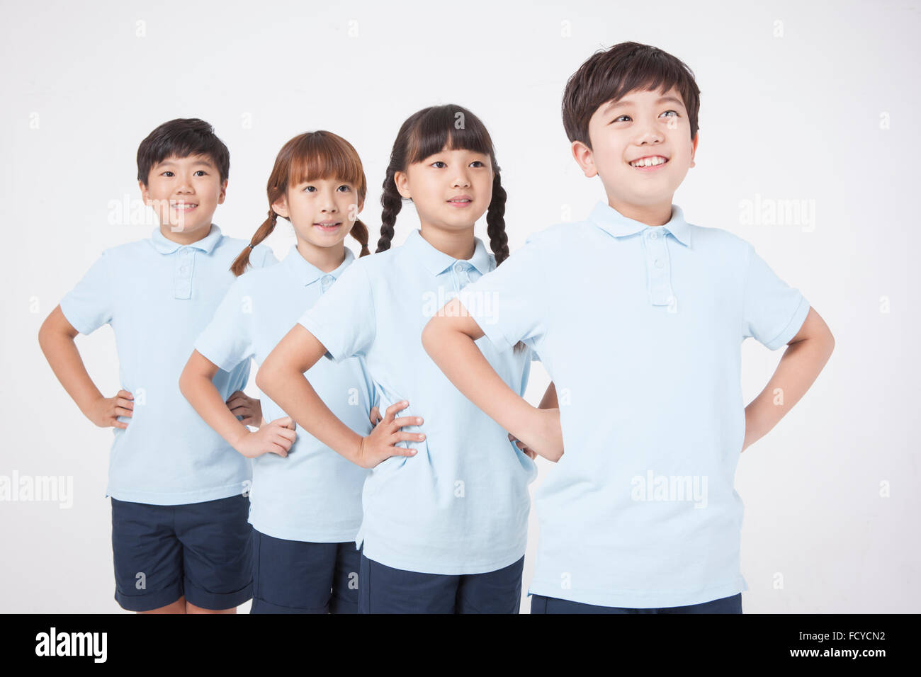 Four elementary school students in sportswear lined up with their hands on their waist and looking up Stock Photo