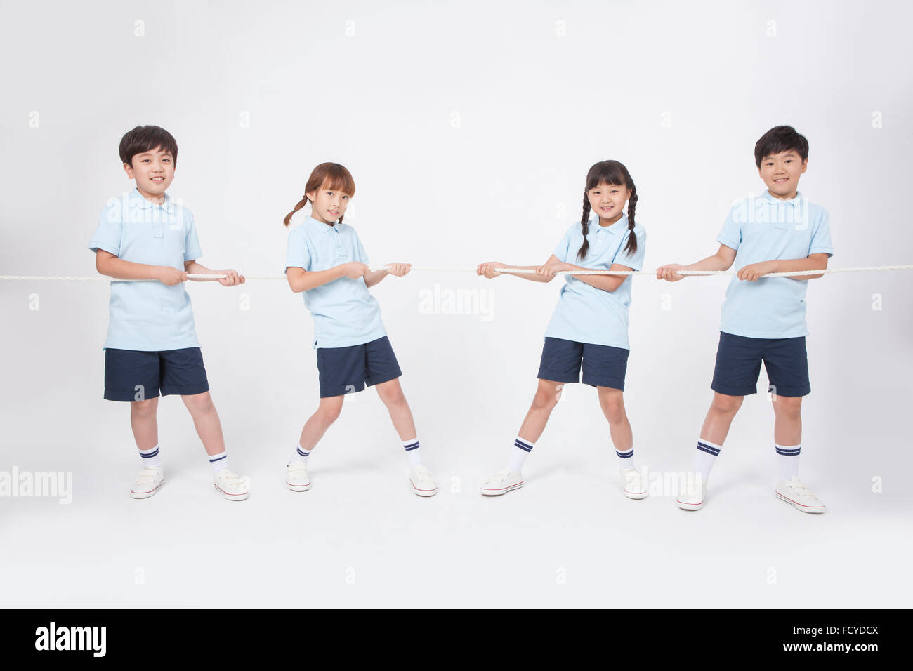Four elementary school students in sportswear doing tug of war into two teams Stock Photo