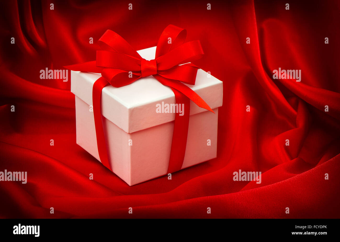 Gift box with bow ribbon on red silk background Stock Photo - Alamy