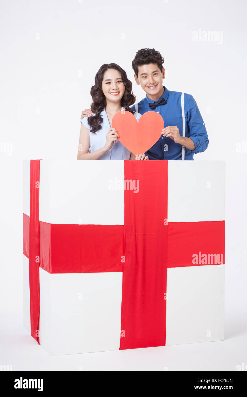 Couple in retro style fashion holding a heart shape and smiling in a ...