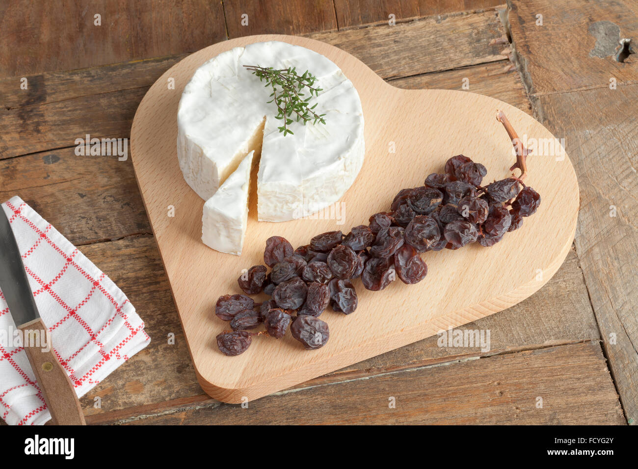 Camembert cheese with a twig of muscat raisins on a heart shaped cheese board Stock Photo