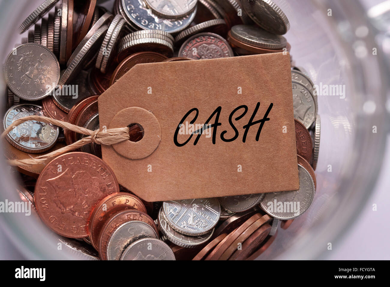 Cash label on British mixed coins inside a glass jar concept Stock Photo