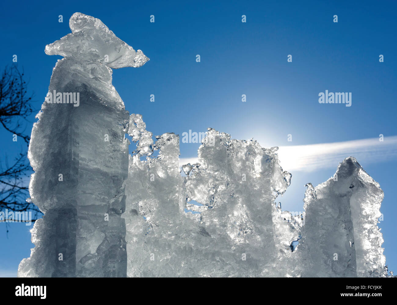 Melting glacial block of ice with sun behind on blue sky background. Stock Photo