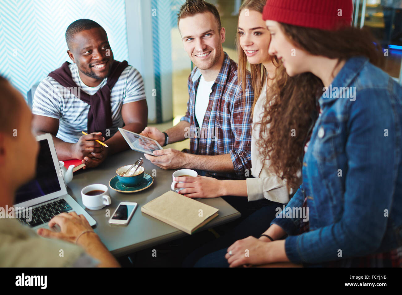 Modern teenagers working with gadgets and talking in cafe Stock Photo