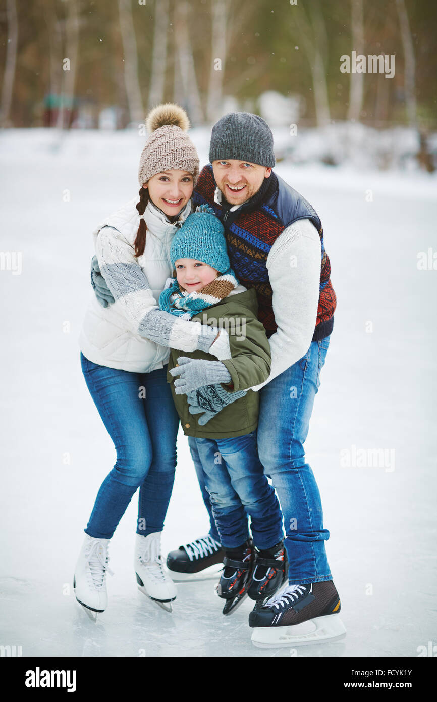 Active family on skates standing in embrace on the rink in natural environment Stock Photo