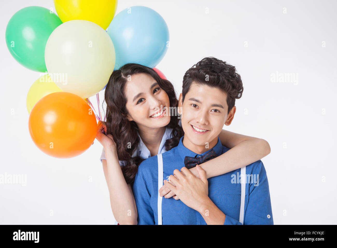 Hugging Balloons Woman with colorful balloons hugging from behind a man and both staring ...