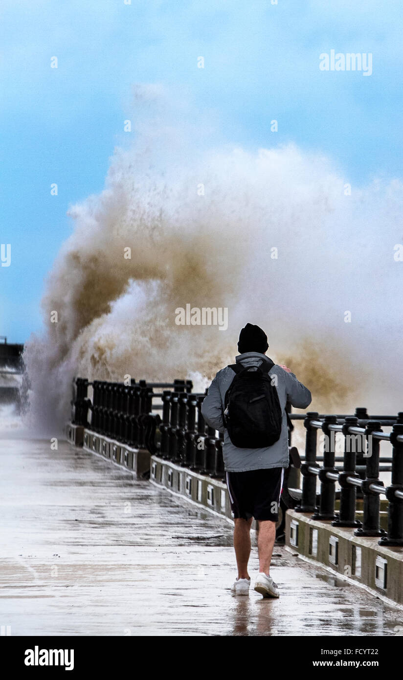 New Brighton, Birkenhead, Liverpool, UK. 26th January 2016. UK weather. Man risks high waves as they crash against the sea defences at Birkenhead Stock Photo