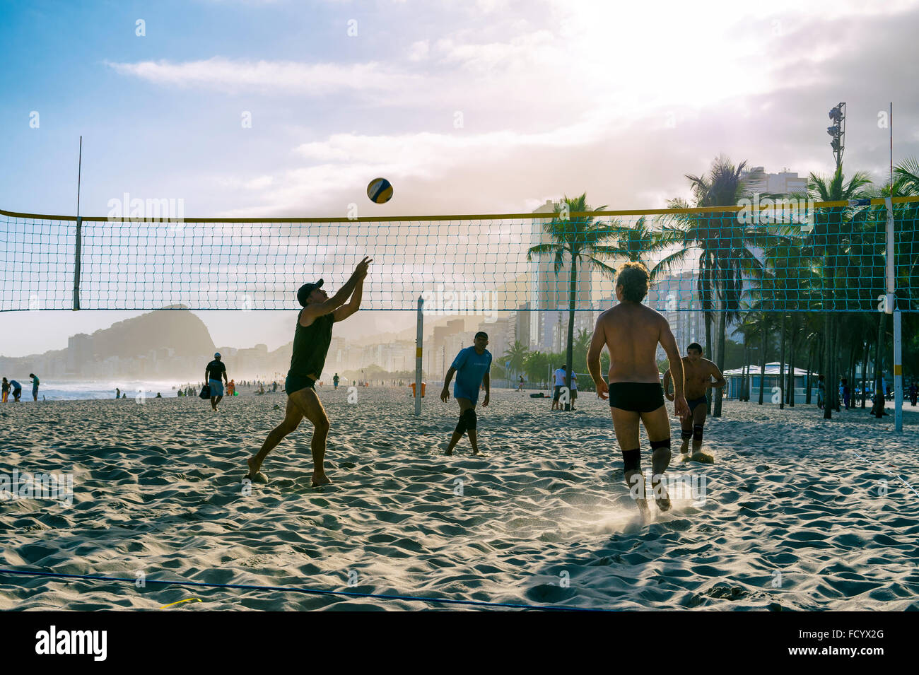 RIO DE JANEIRO - OCTOBER 30, 2015: A group of young Brazilian men play a game of volleyball at sunset at the Leme, Copacabana. Stock Photo