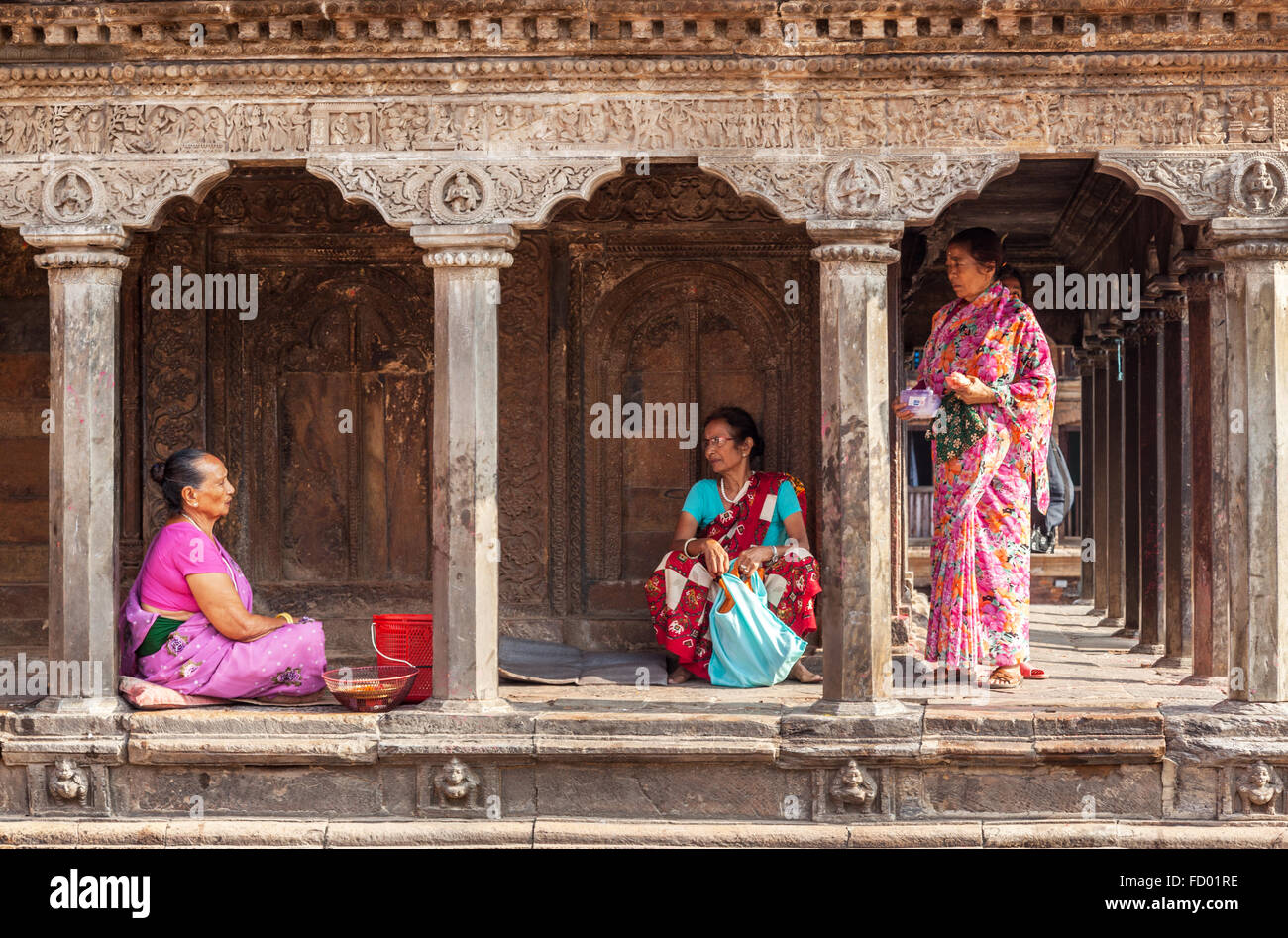 Three women talking outside a temple in Patan Stock Photo