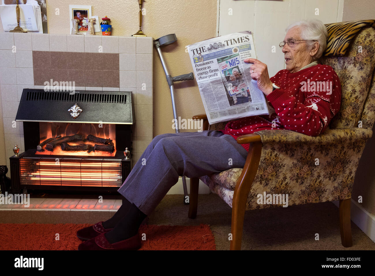 Old age pensioner at home reading The Times newspaper with the headline 'Pensioners freeze as energy firms chase profit' Stock Photo