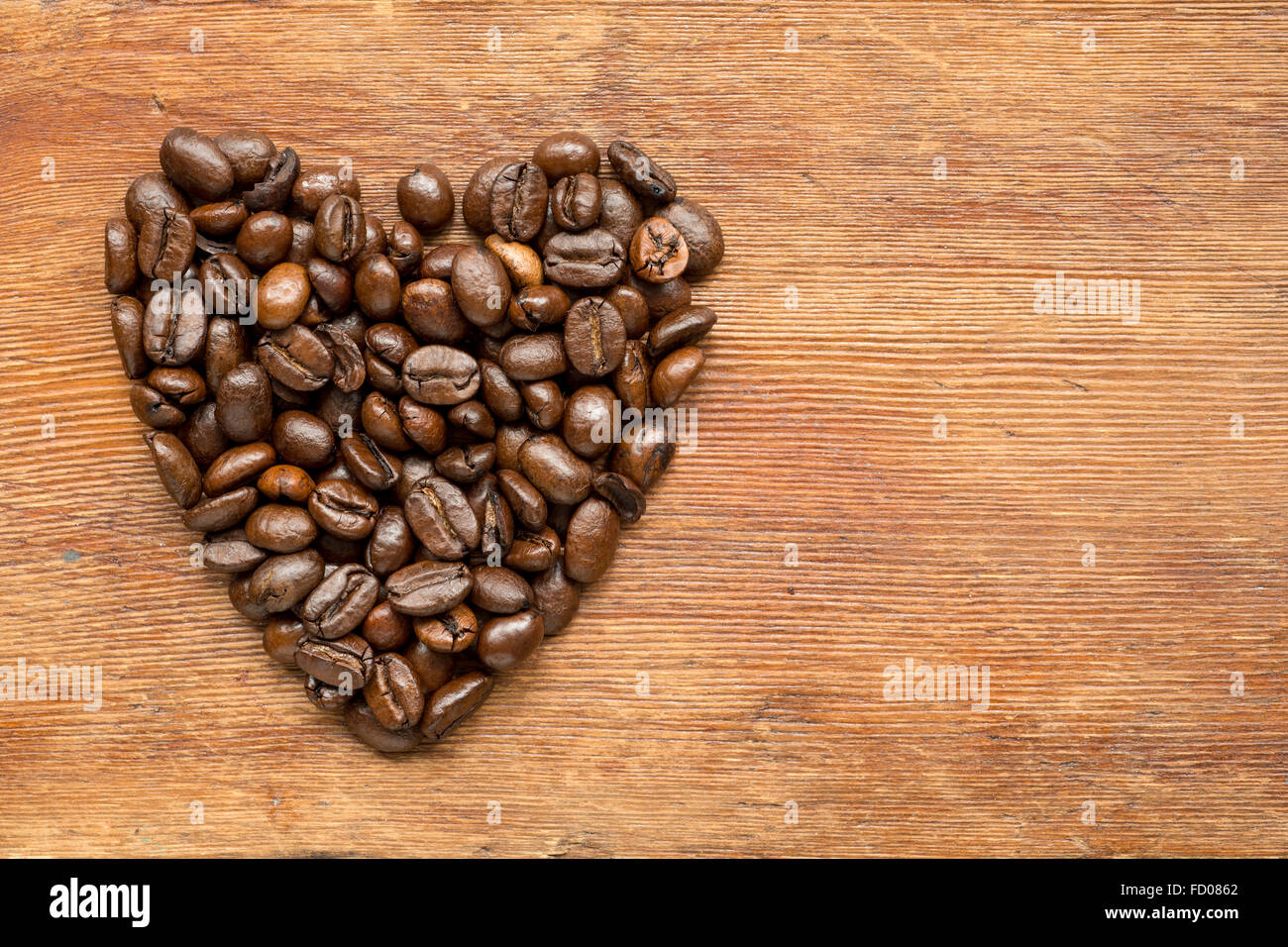 coffee heart symbol made from roasted grains on vintage wooden surface Stock Photo