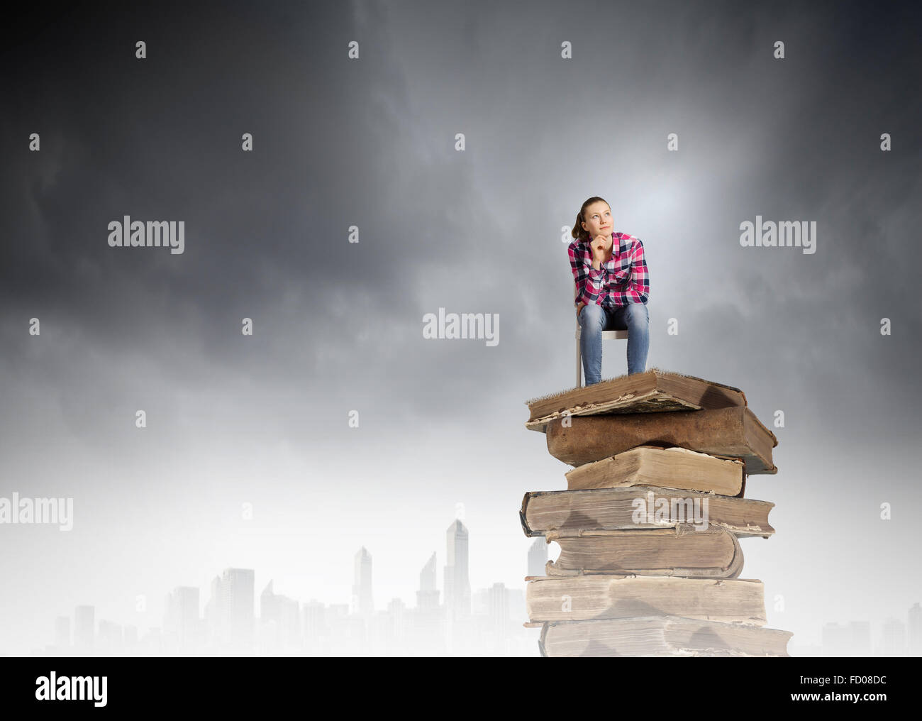Young girl sitting on high pile of books Stock Photo - Alamy