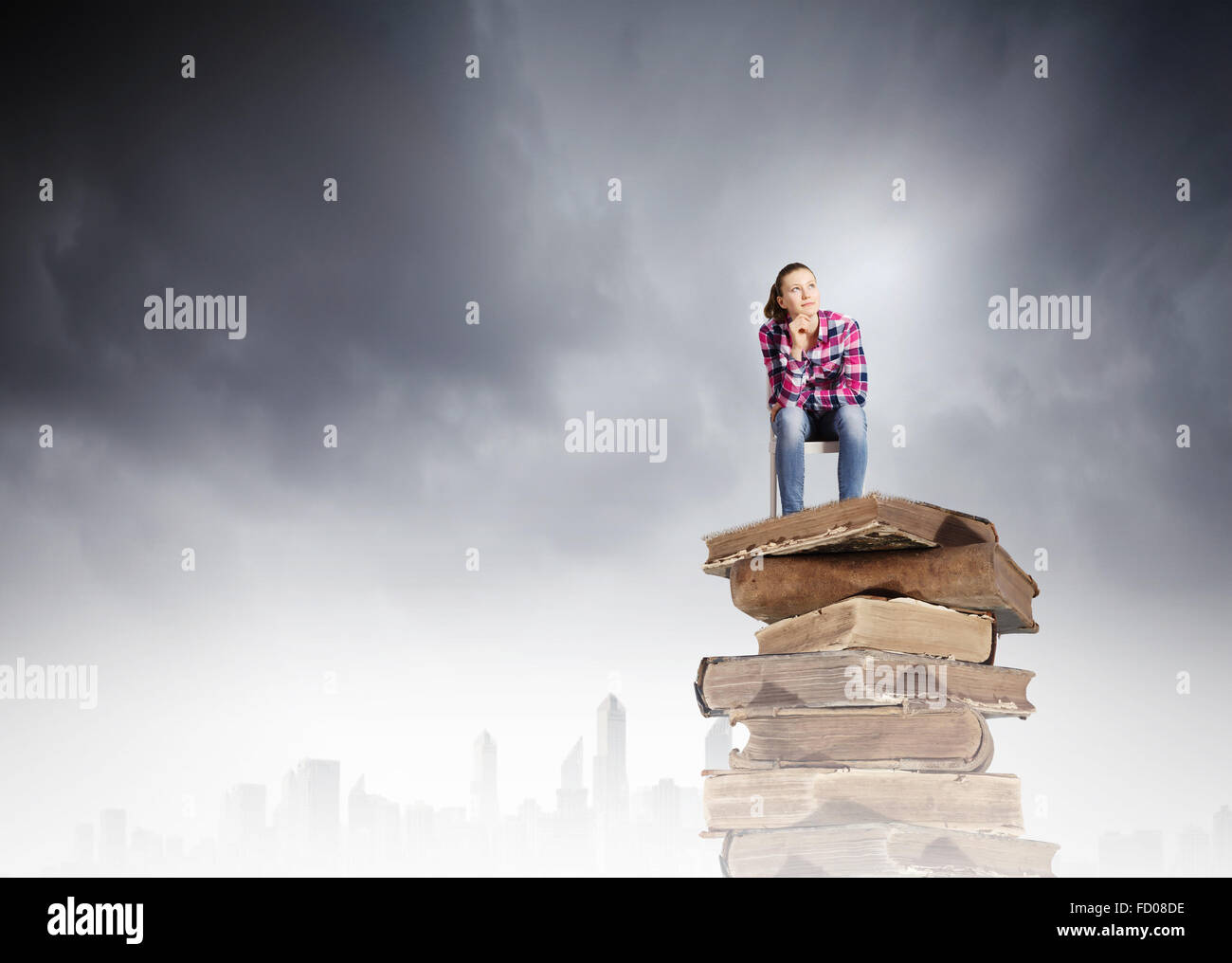 Young girl sitting on high pile of books Stock Photo - Alamy