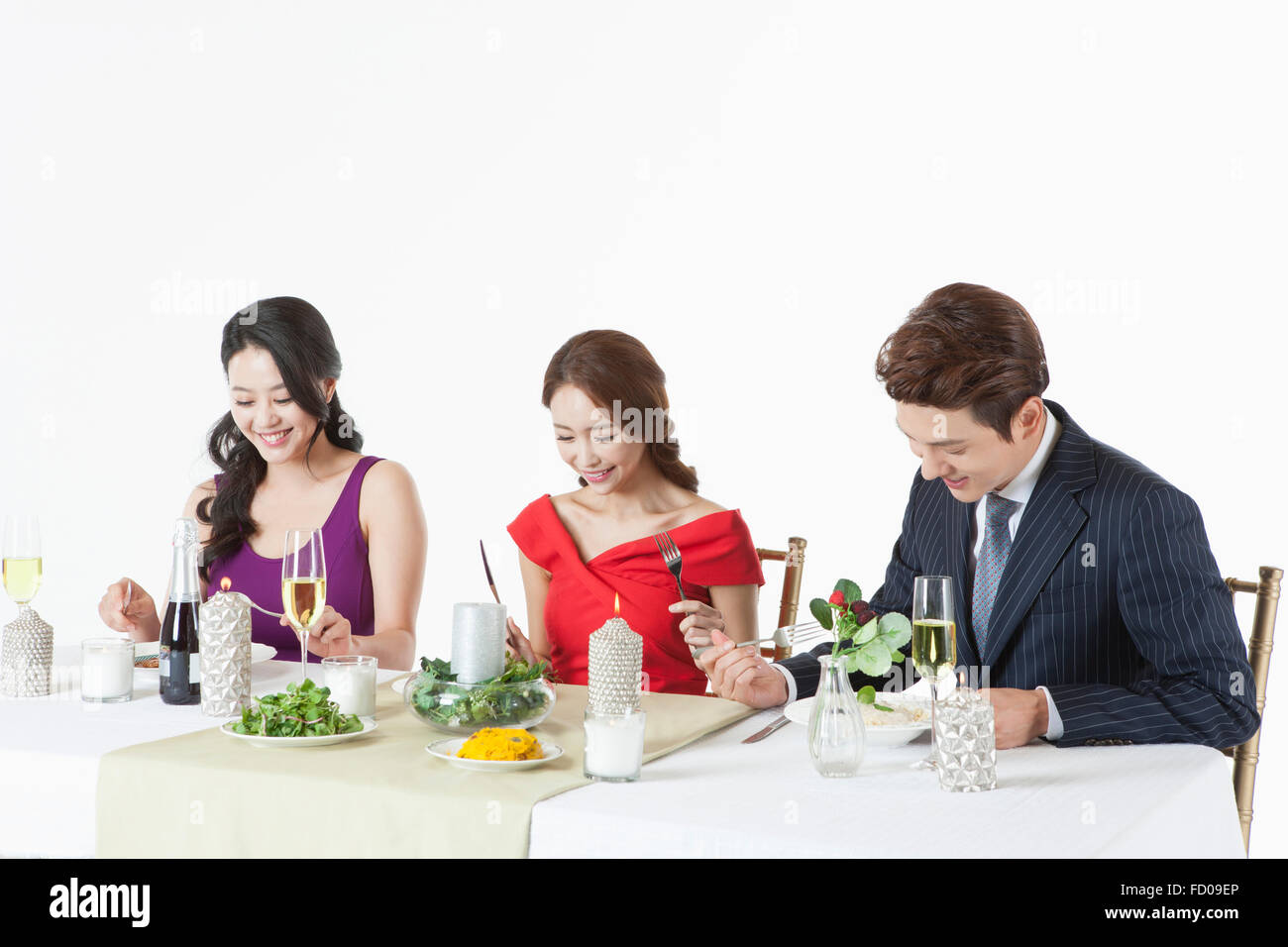 Three adults seated at table being ready to eat enjoying a party Stock Photo