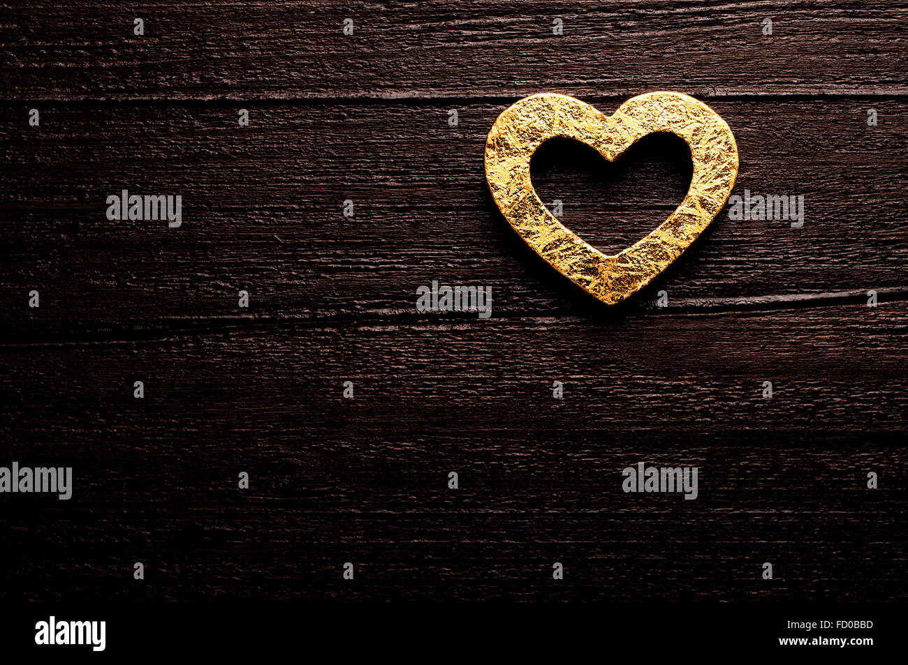 Golden heart on dark wooden background Stock Photo