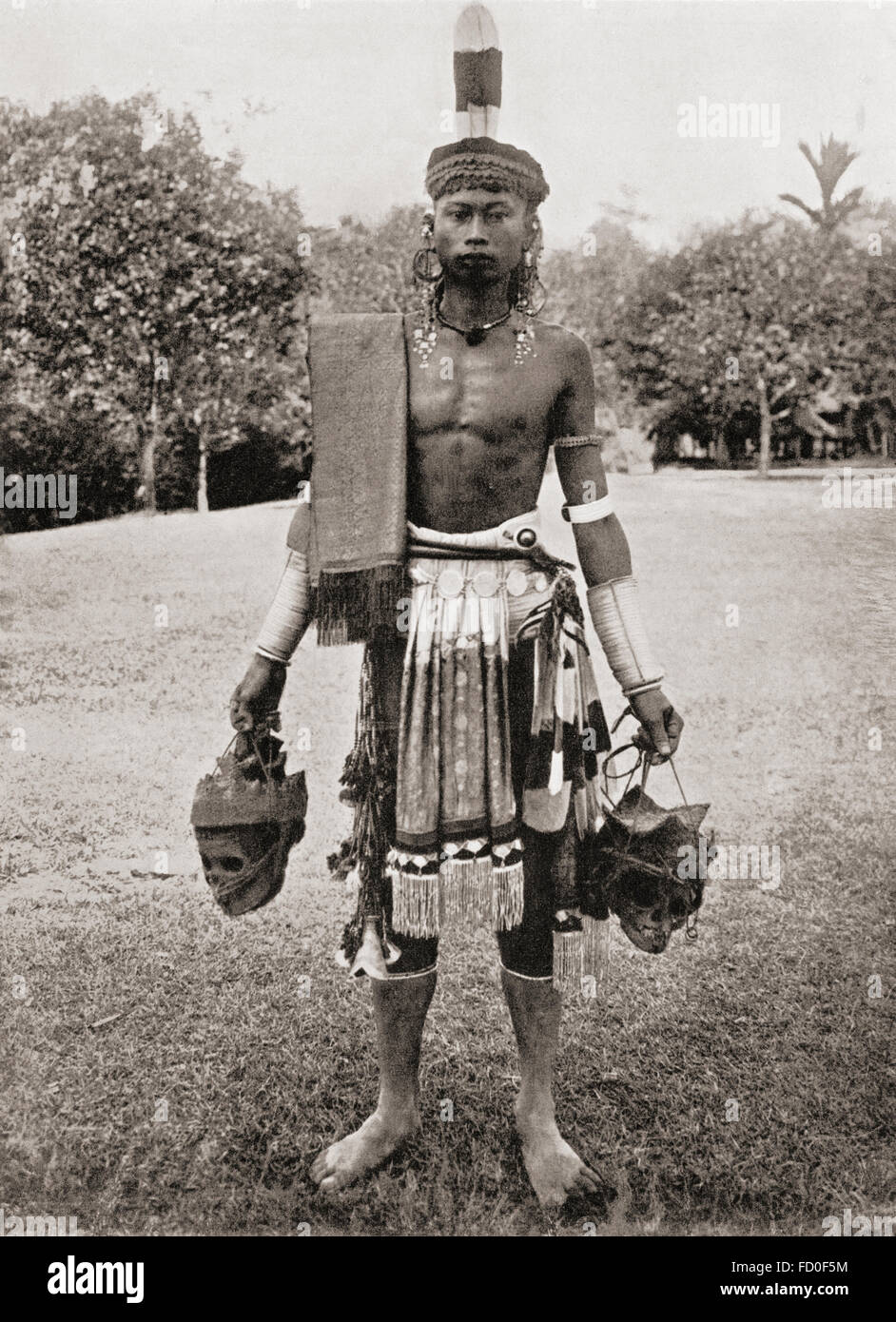 A Dayak, Dyak or Dayuh man from the island of Borneo, seen here in gala costume.  Every year or two the Dayaks hold a feast called Gawai Autu in honour of the departed spirits which they believe surround the heads which hang in their houses.  After a 19th century photograph. Stock Photo