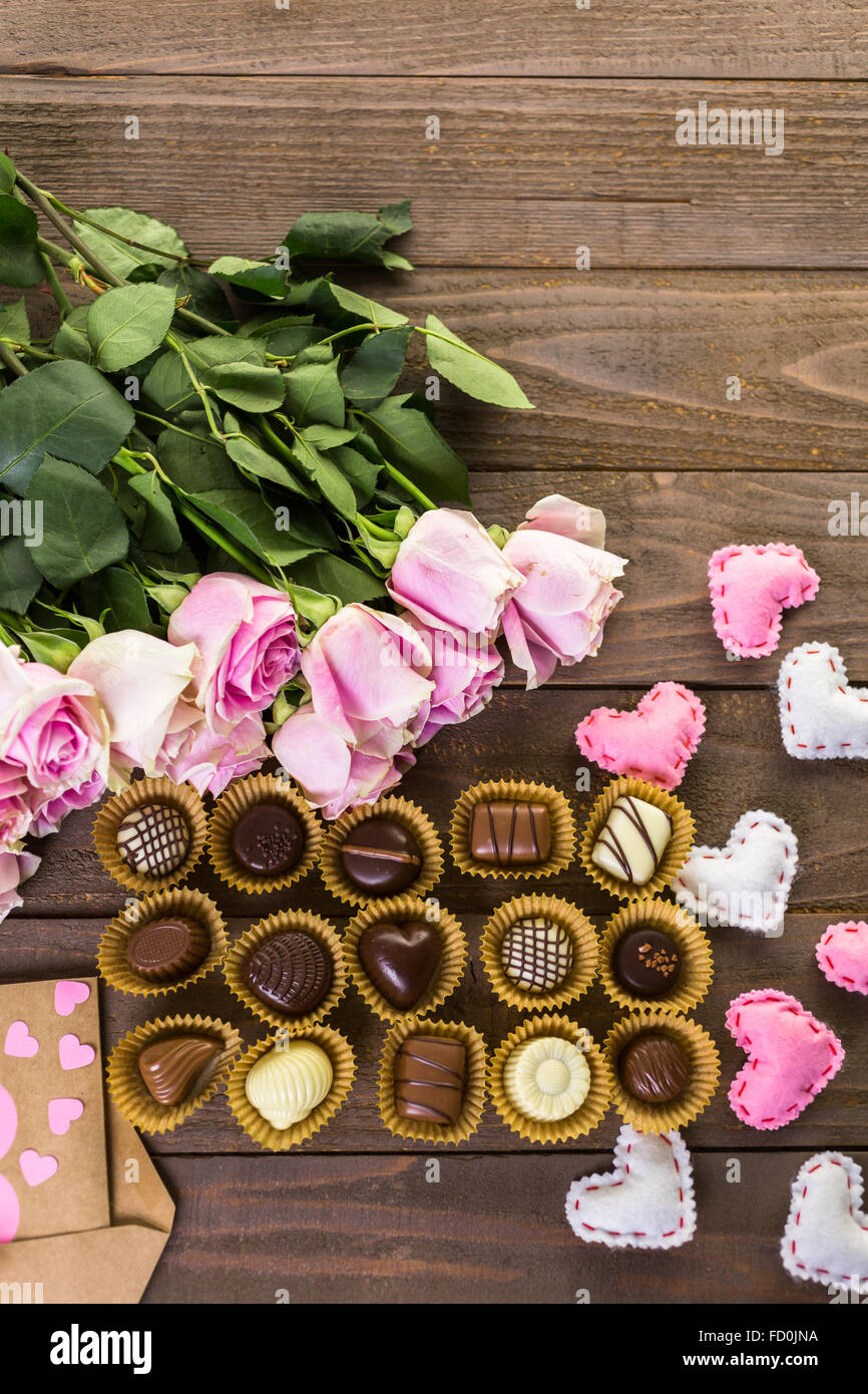 Assorted chocolated with pink roses on wood table Stock Photo - Alamy