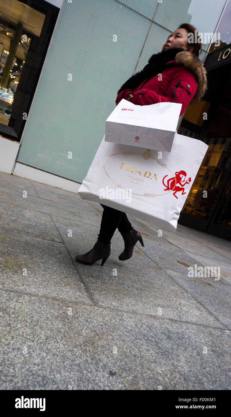 A woman walks up Fifth Avenue in New York on Friday, January 22, 2016 with her purchase from the luxury goods retailer Prada. (© Richard B. Levine) Stock Photo
