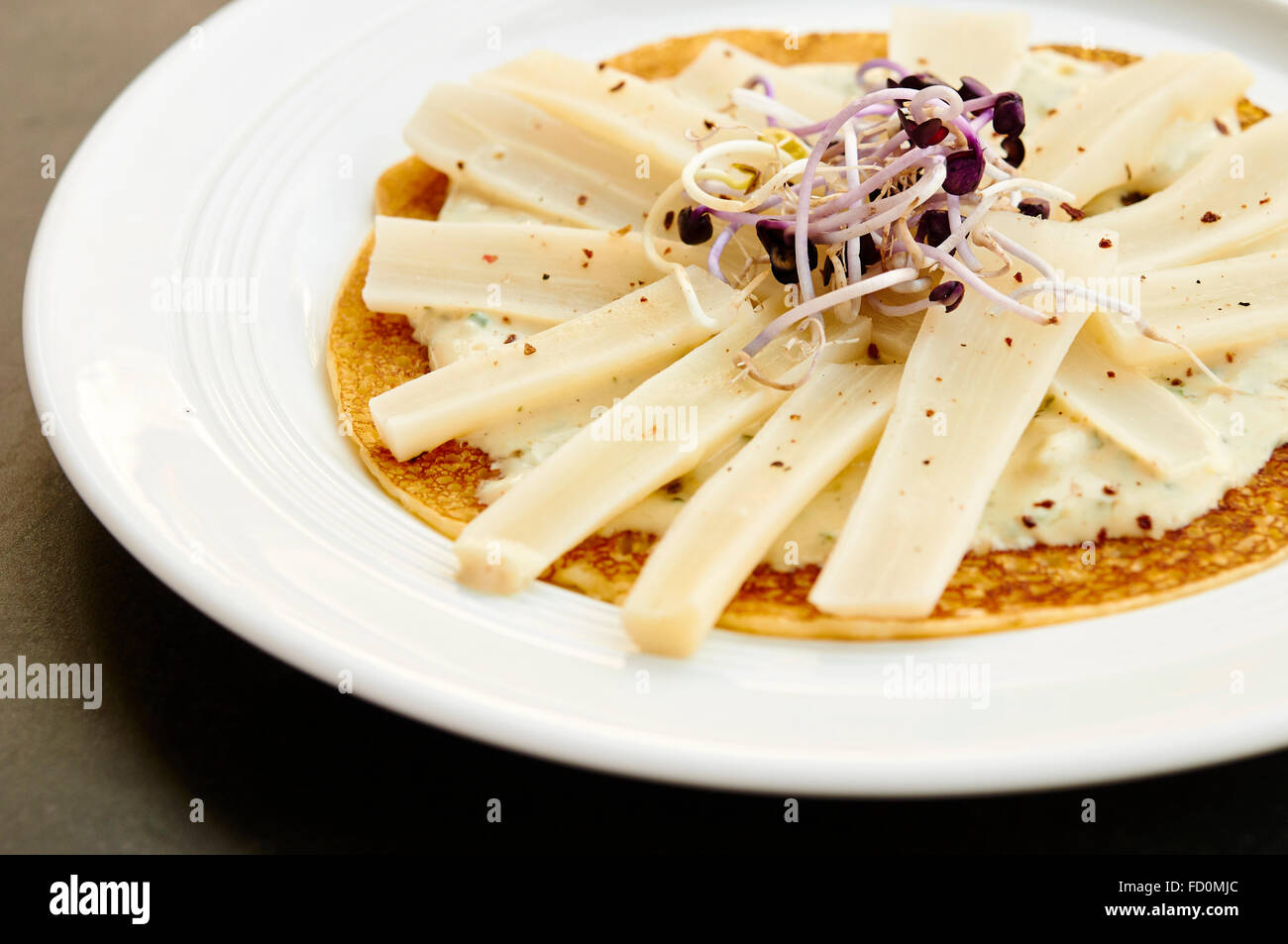 Plate with black salsify with radish sprouts on a crepe. Stock Photo