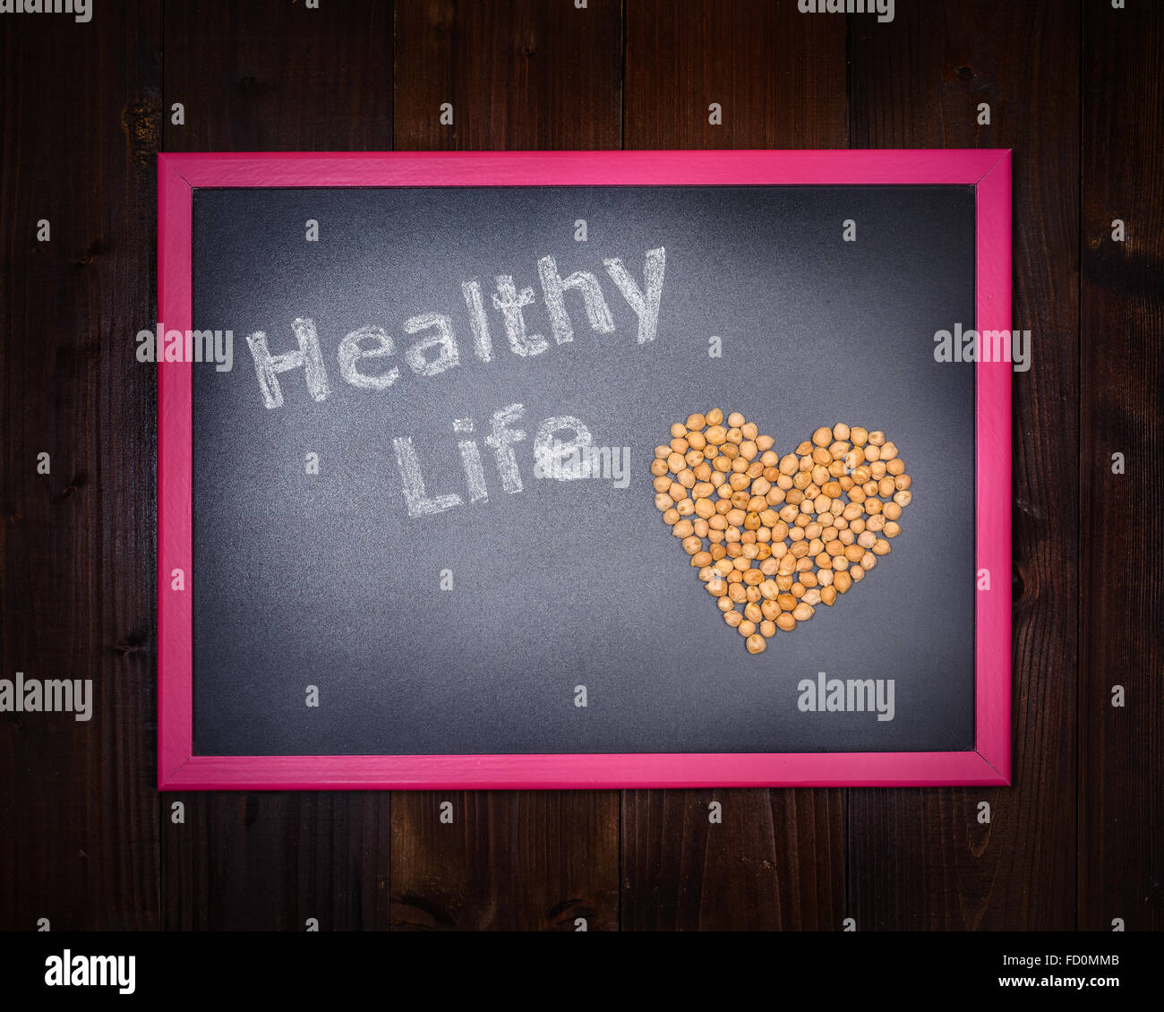 In the picture a blackboard, on the left side with written 'Healthy Life' and chickpeas on the right side, drawing a heart on wo Stock Photo
