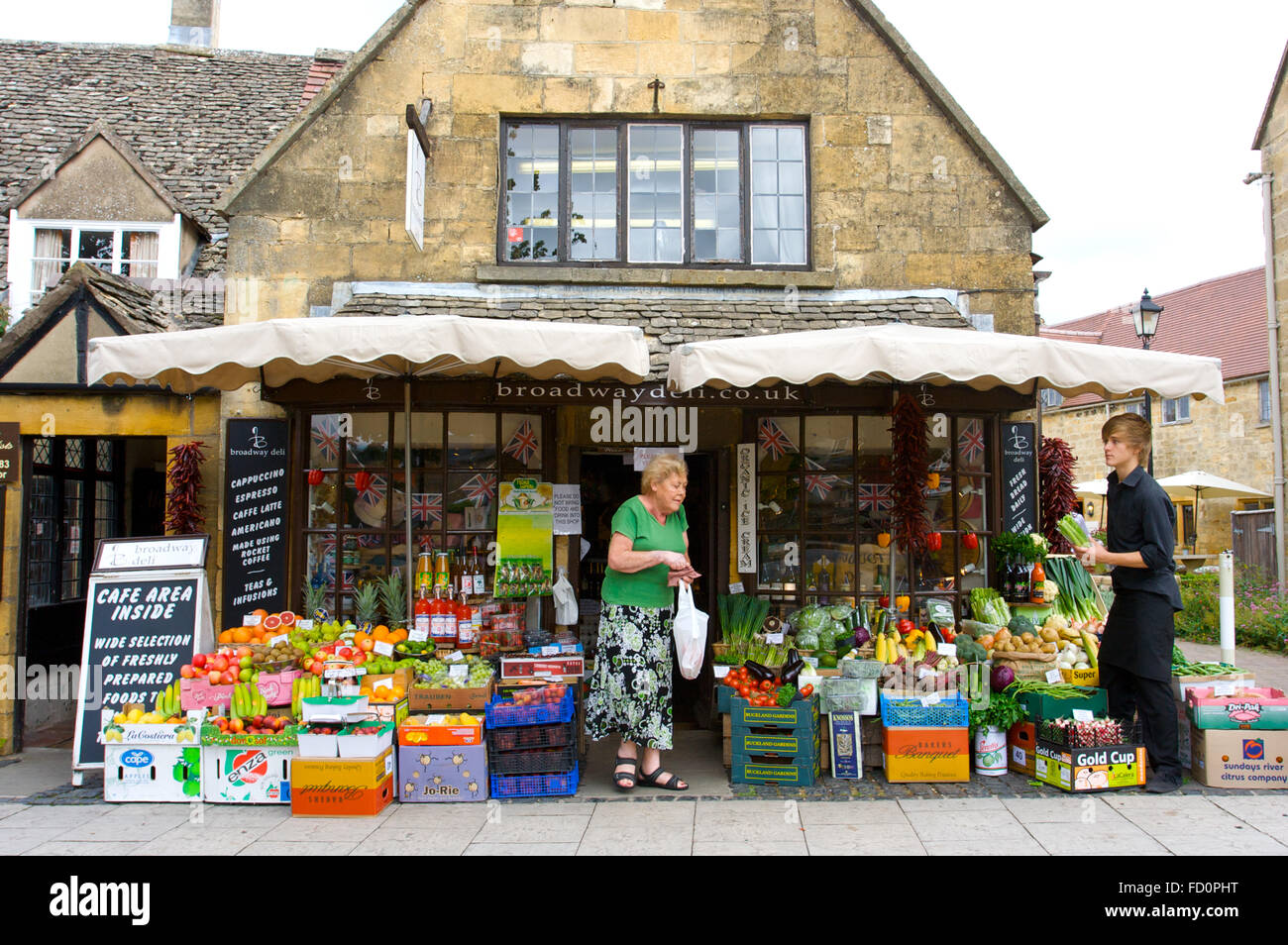 An elderly lady and shop keeper at broadwaydeli shop on the High Street in Broadway village centre, Cotswolds, UK. Stock Photo