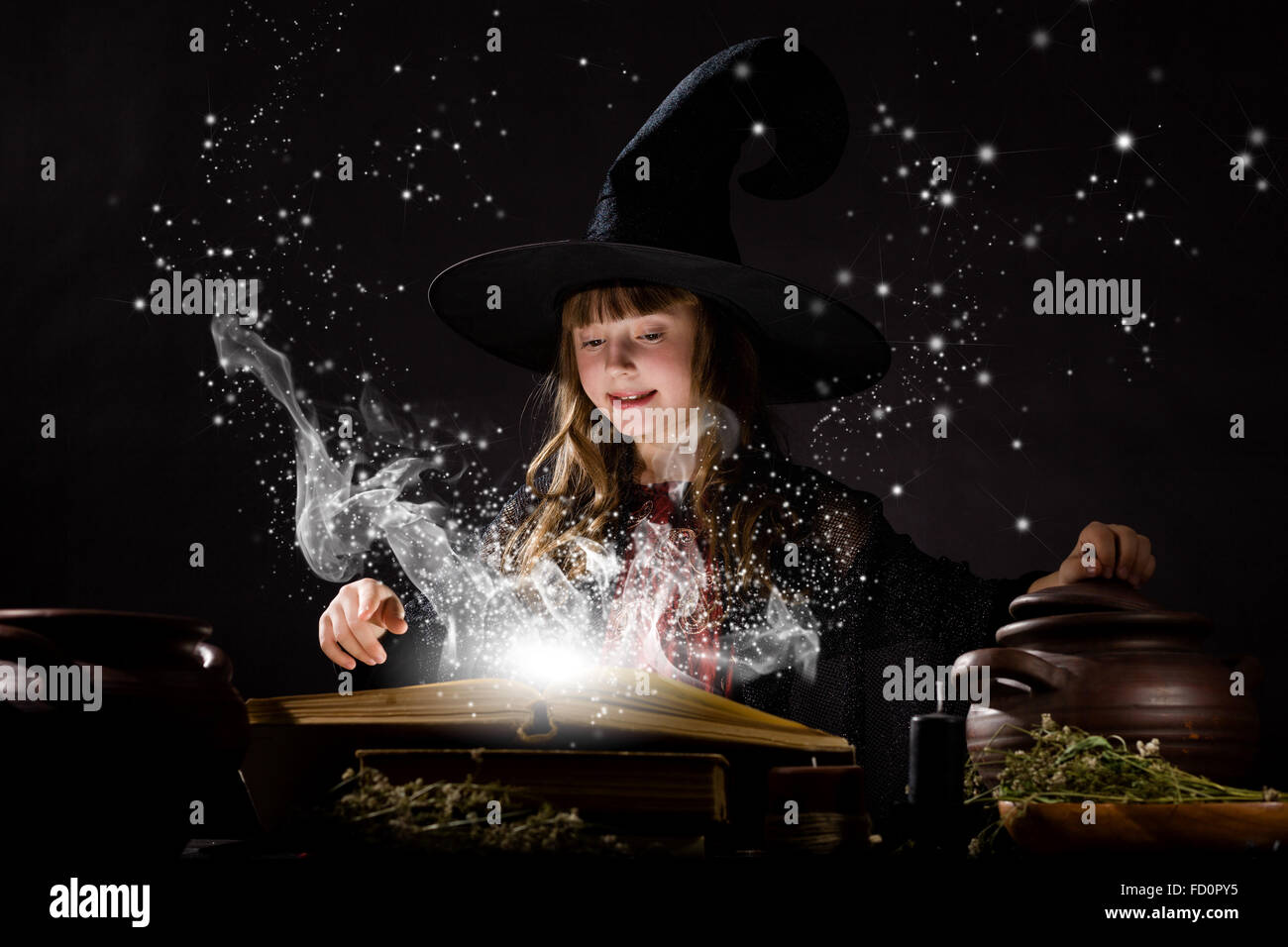 Little Halloween witch making magic with stick Stock Photo - Alamy