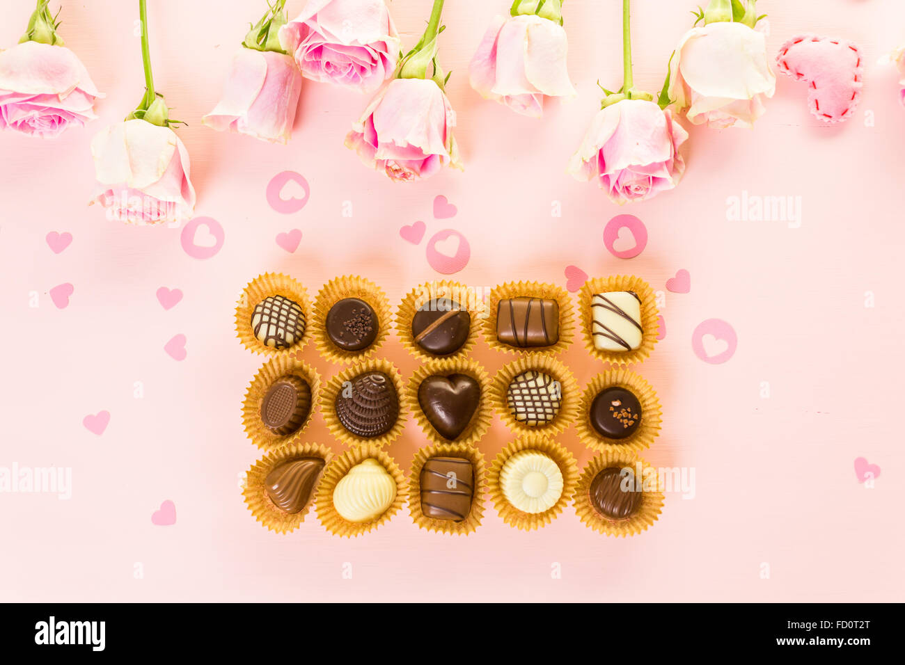 Assorted chocolates with pink roses on pink background Stock Photo - Alamy