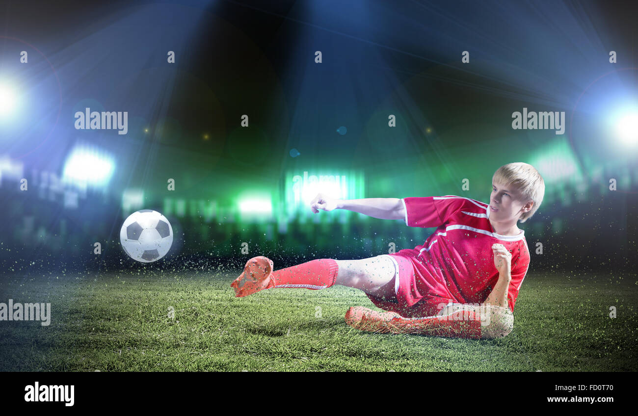 Young football player on stadium doing slide tackle Stock Photo Alamy