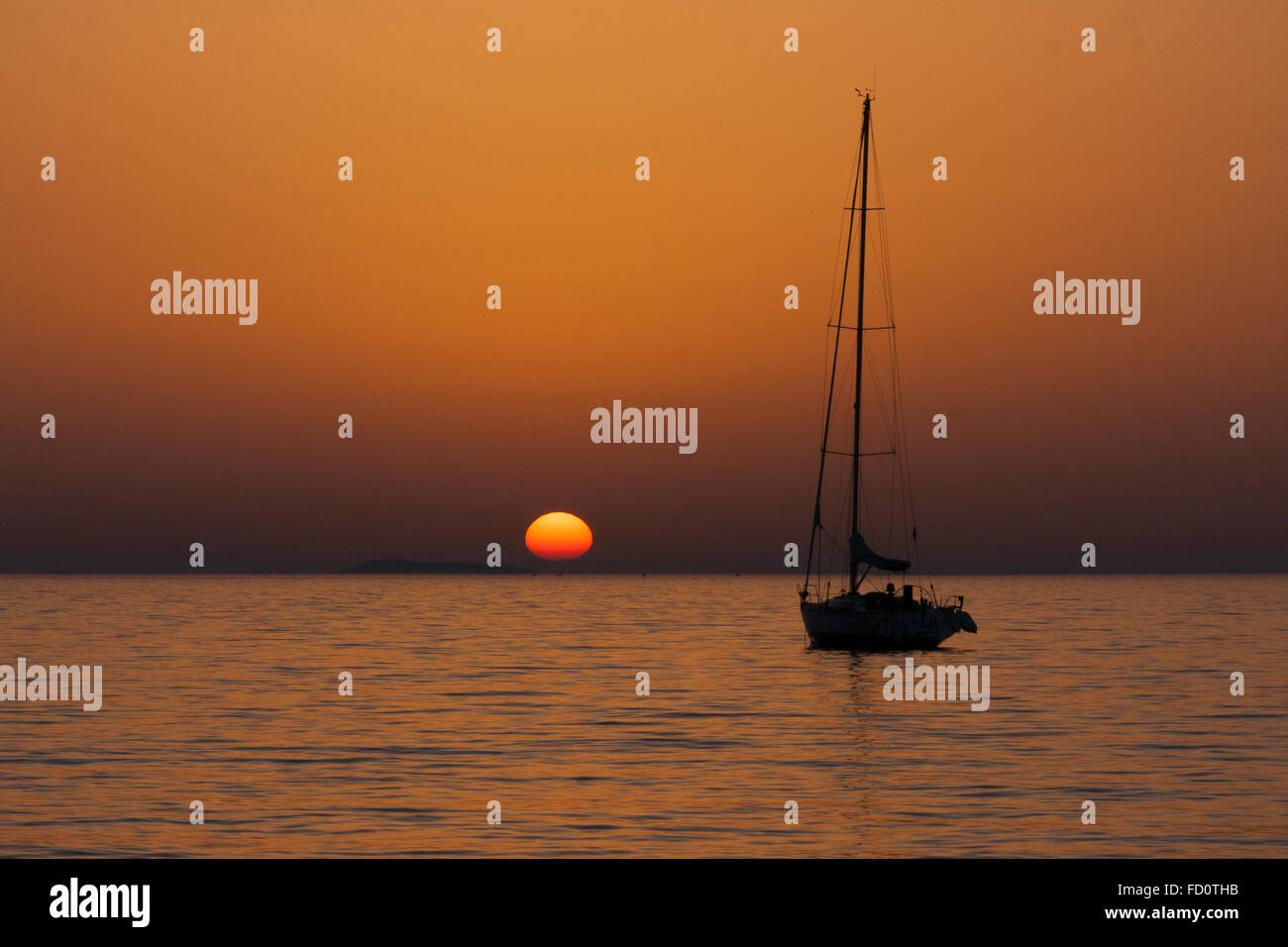 fading sun sunset at sea with yacht silhouette Stock Photo