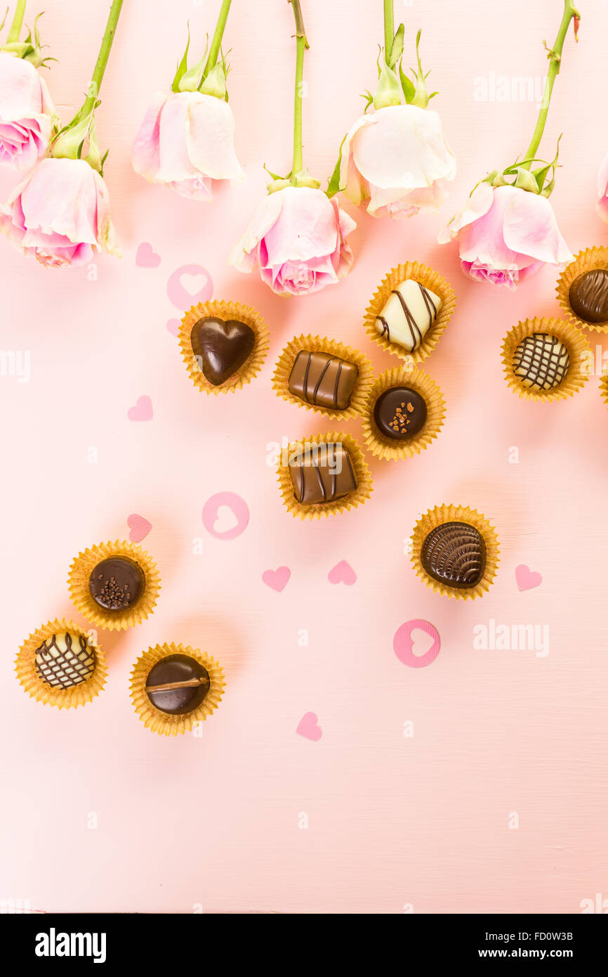 Assorted chocolates with pink roses on pink background Stock Photo - Alamy