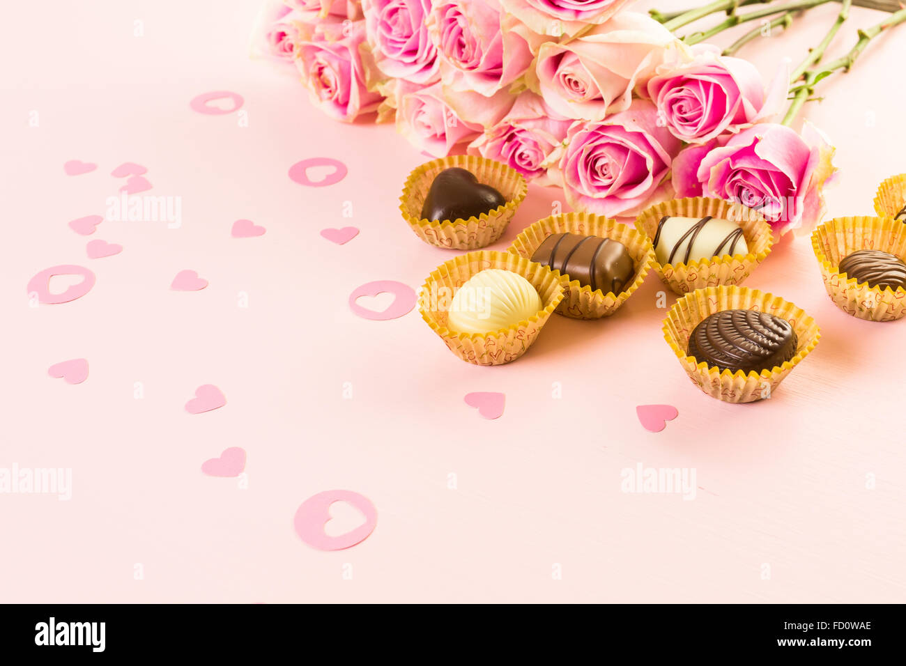 Assorted chocolates with pink roses on pink background Stock Photo - Alamy