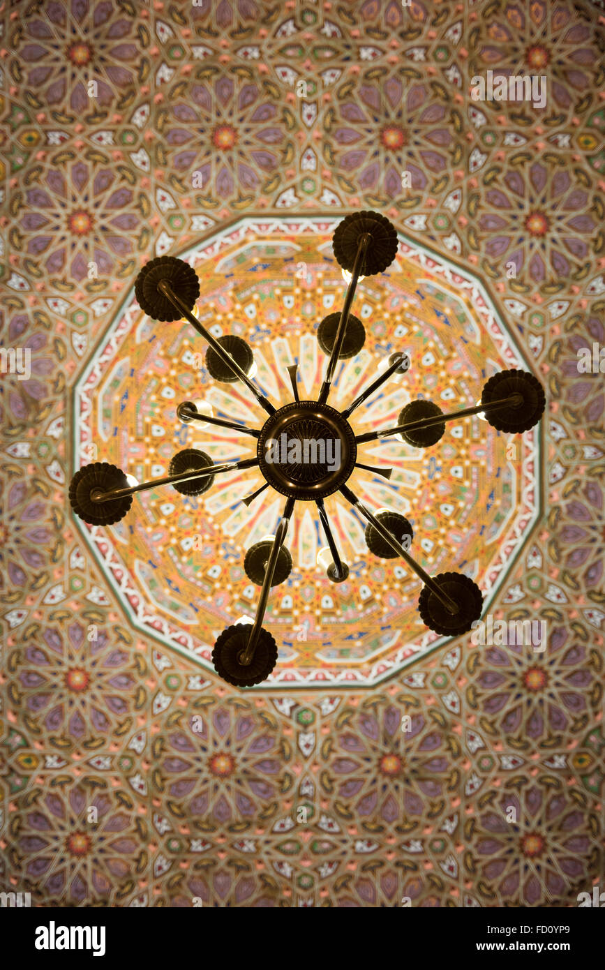 A chandelier hanging of a carved by hand ceiling in a home in Fez Stock Photo