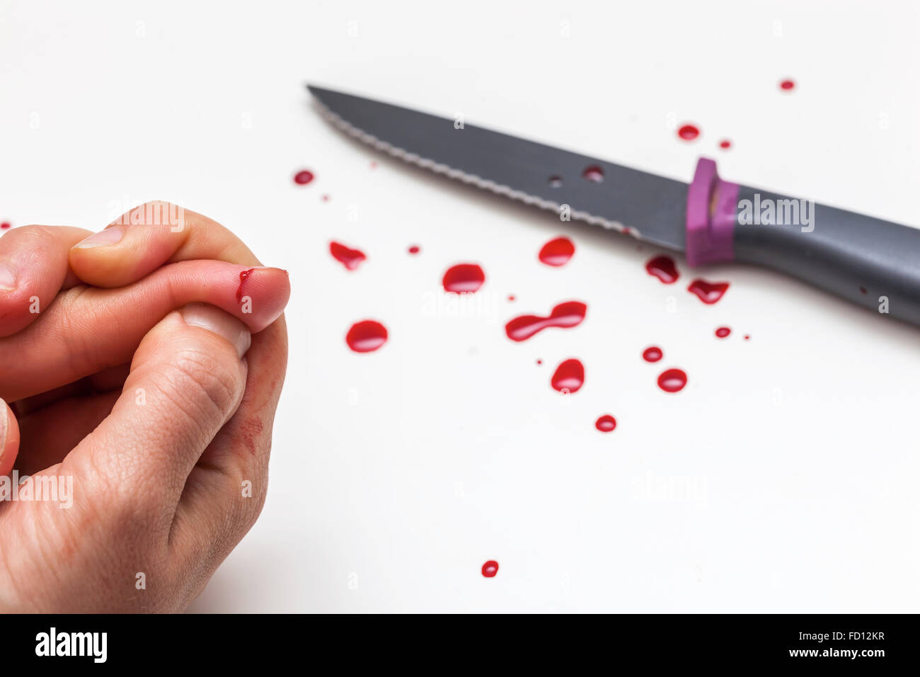 Hand, knife and drops of blood on a white surface Stock Photo