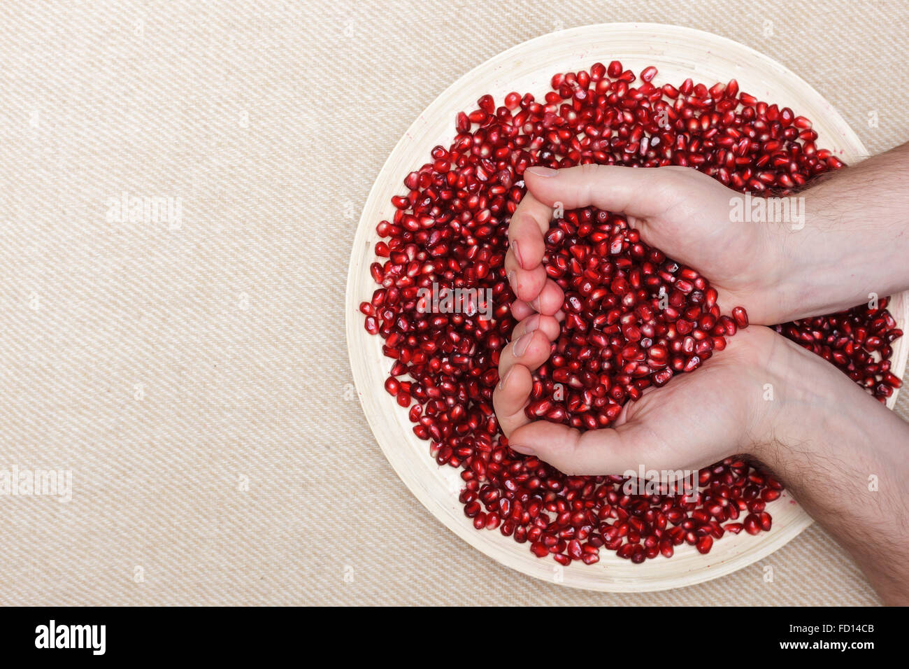 Full plate of peeled pomegranate seeds and a man holding them in shape of heart Stock Photo