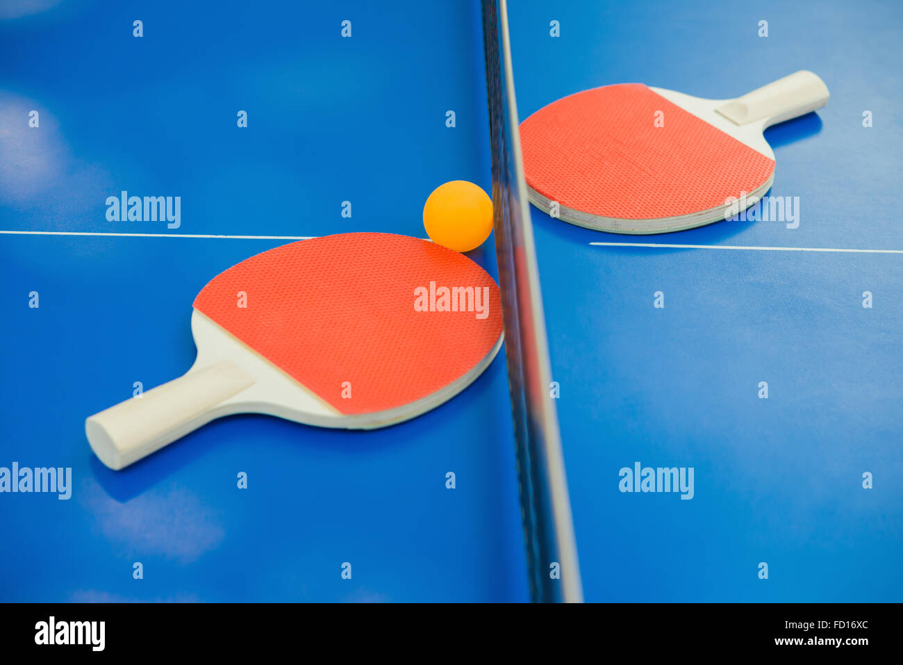 pingpong rackets and ball and net on a blue pingpong table Stock Photo