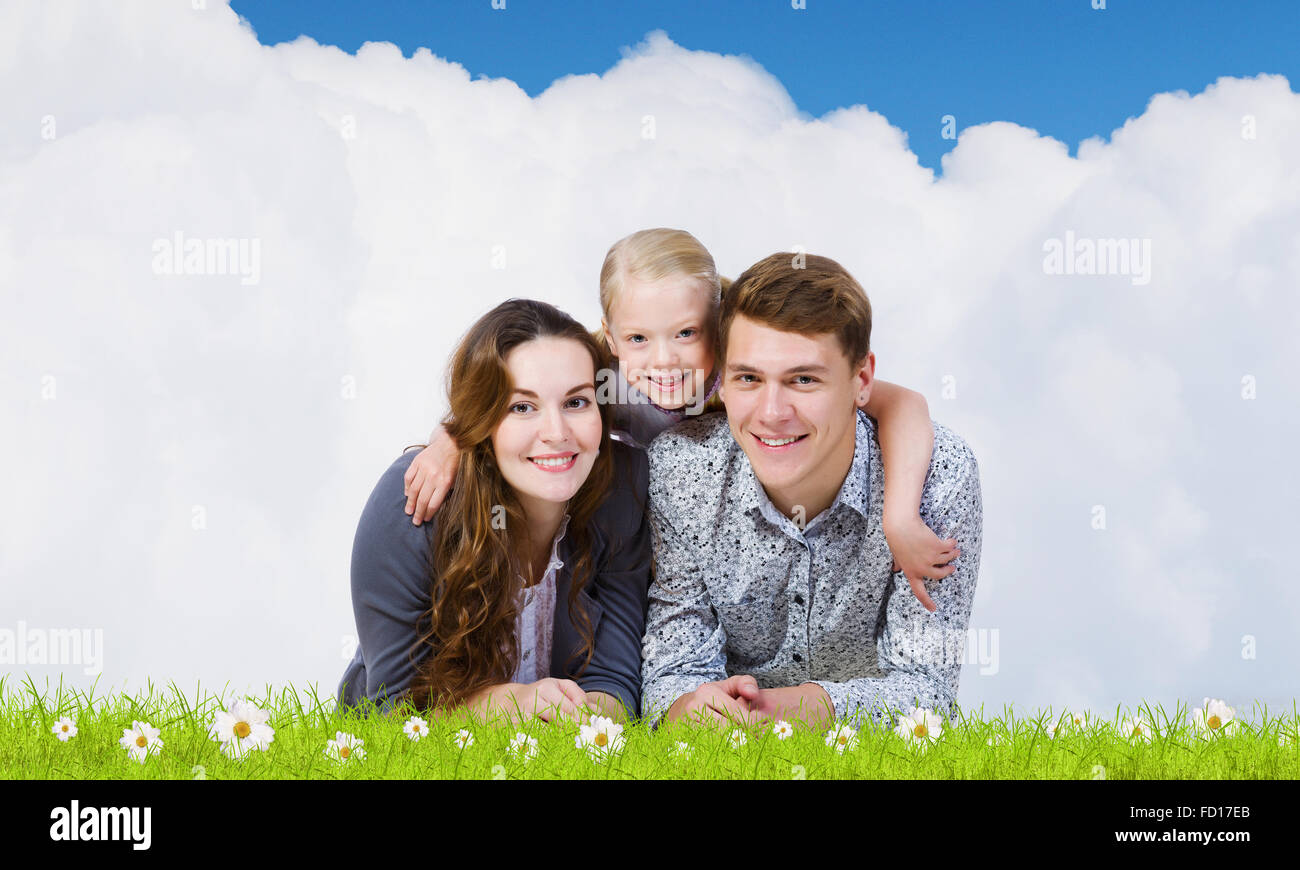 Happy family of three lying on green grass Stock Photo