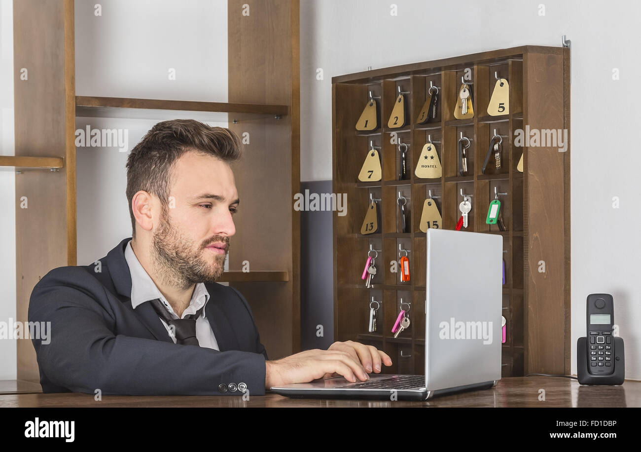 Portrait of a receptionist working on a computer at his desk Stock ...