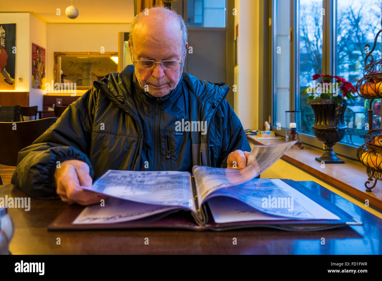 Berlin Zum Schwarzen Ferkel restaurant and bar interior and elderly man reading a menu Stock Photo