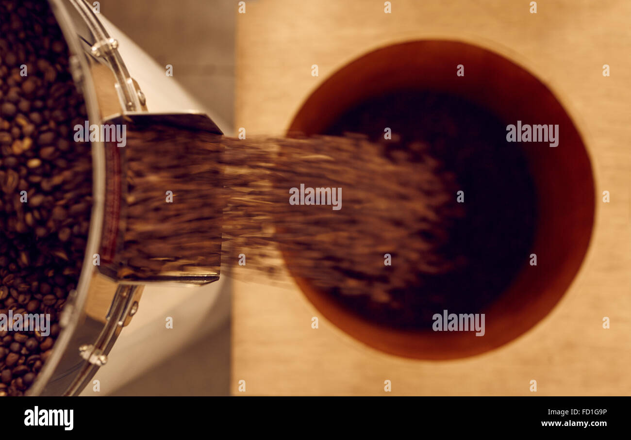 Overhead shot of roasted coffee beans falling into container Stock Photo