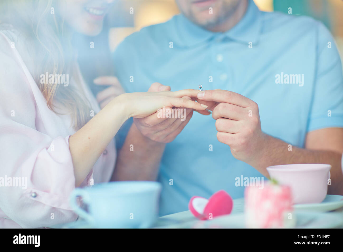 Young man getting engagement ring on his girlfriend finger Stock Photo