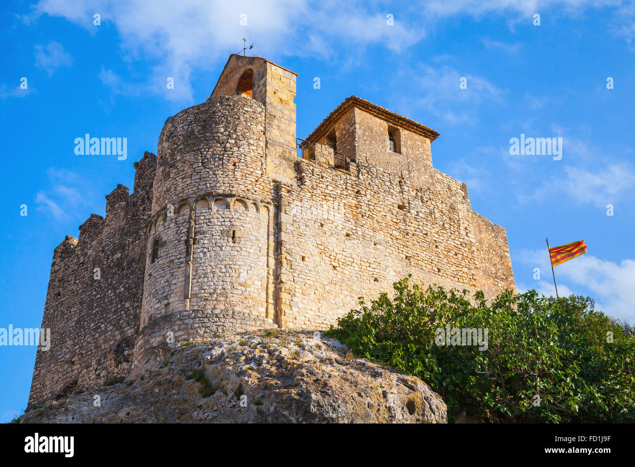 Medieval stone castle and flag of Catalonia on the rock in Spain. Main landmark of Calafell town Stock Photo