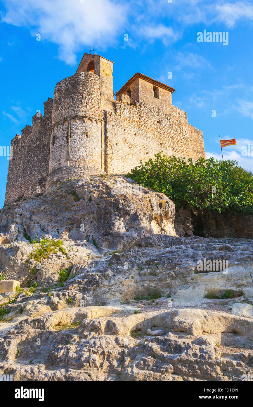 Medieval stone castle and flag of Catalonia on the rock in Spain. Main landmark of Calafell town, vertical photo Stock Photo