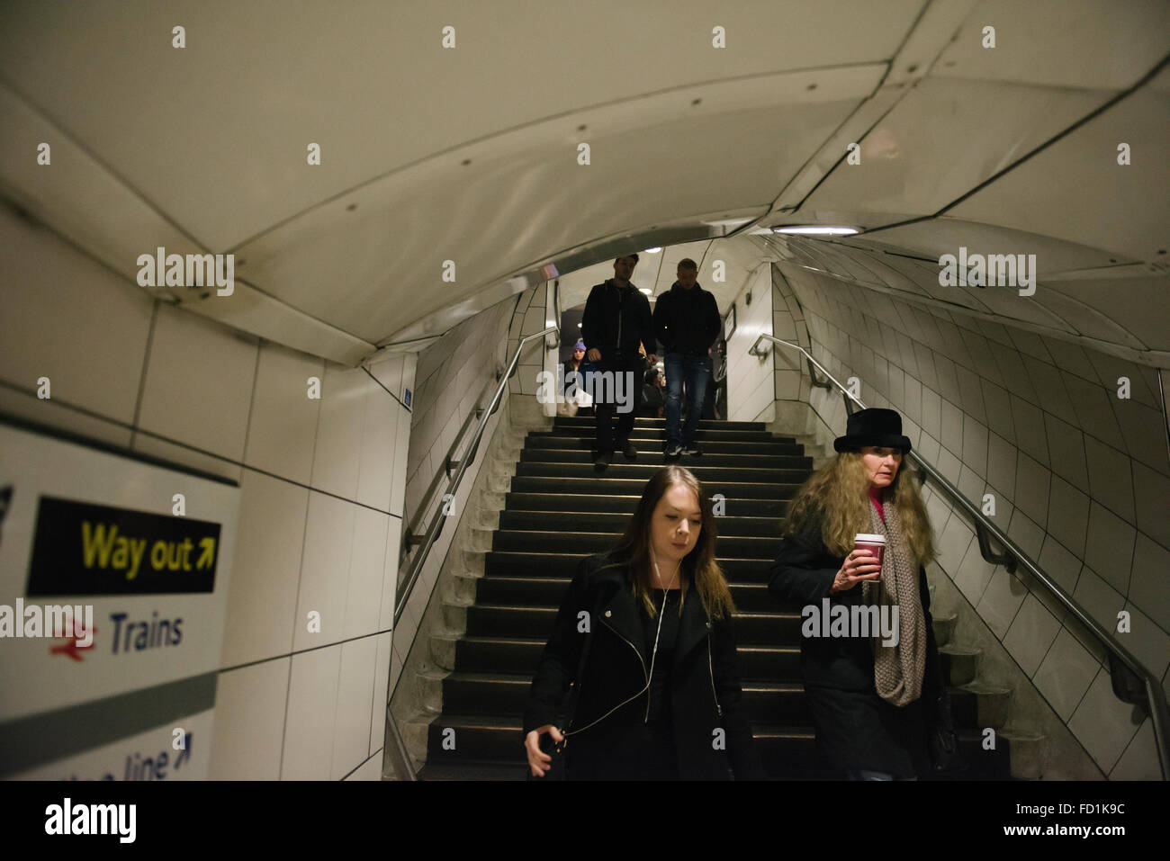 People going down the stairs at the London underground station.  Way out sign on the wall. Stock Photo