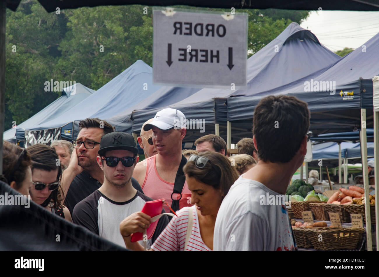 People in a queue to place an order for food at a market stall under an Oder Here sign in Australia Stock Photo